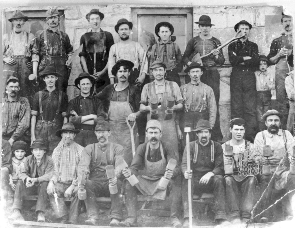 Men working as molders in Sharon Valley. Note the unusual variety of tools used for the compacting of special sand for casting the iron. Note: the children are not just visiting they are part of the work force. - Sharon Historical Society